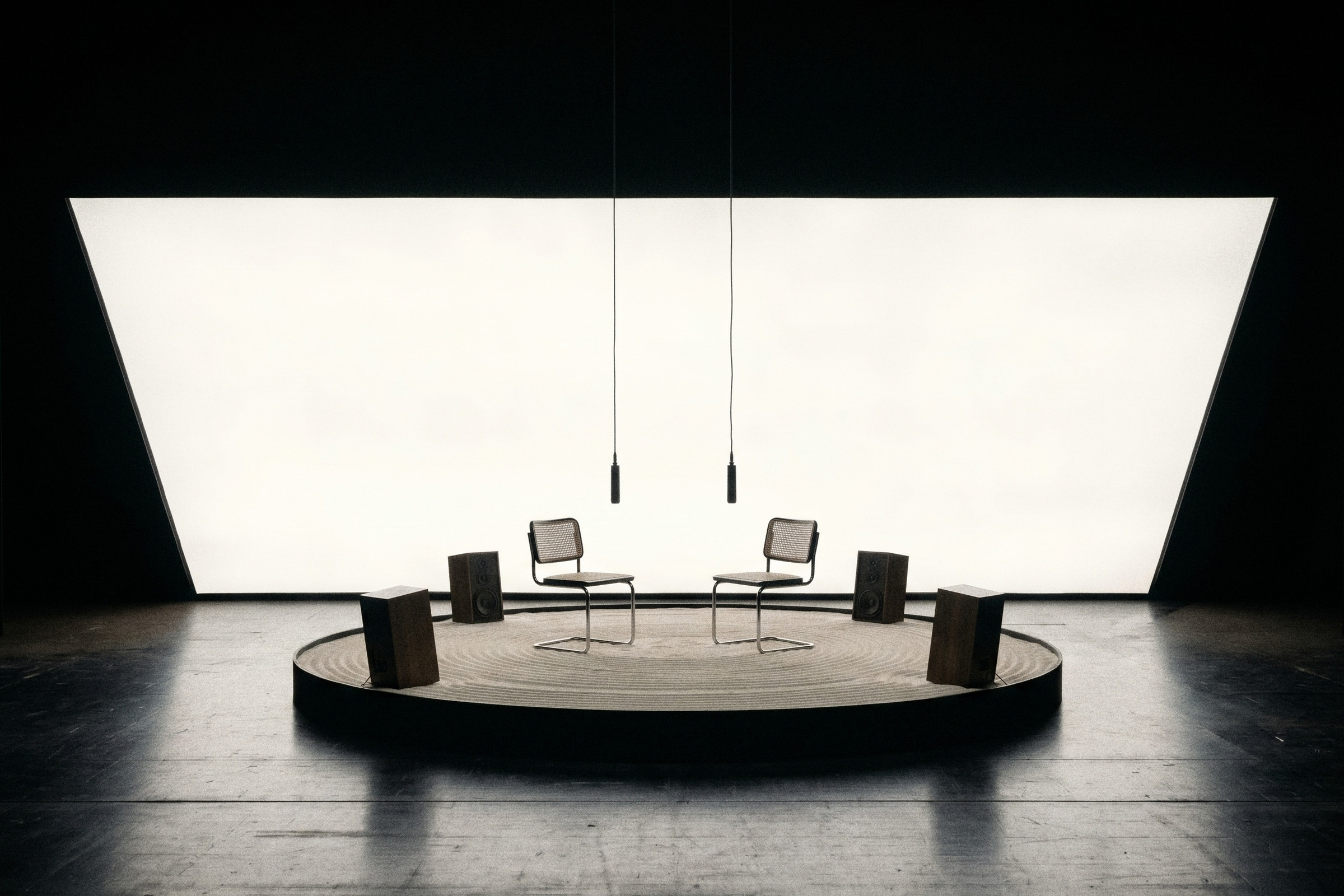 A suspended jacket gives way to two chairs on the same light-wall stage.