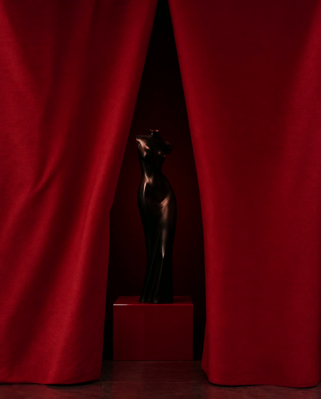 A velvet curtain drawn open on a plaster room.